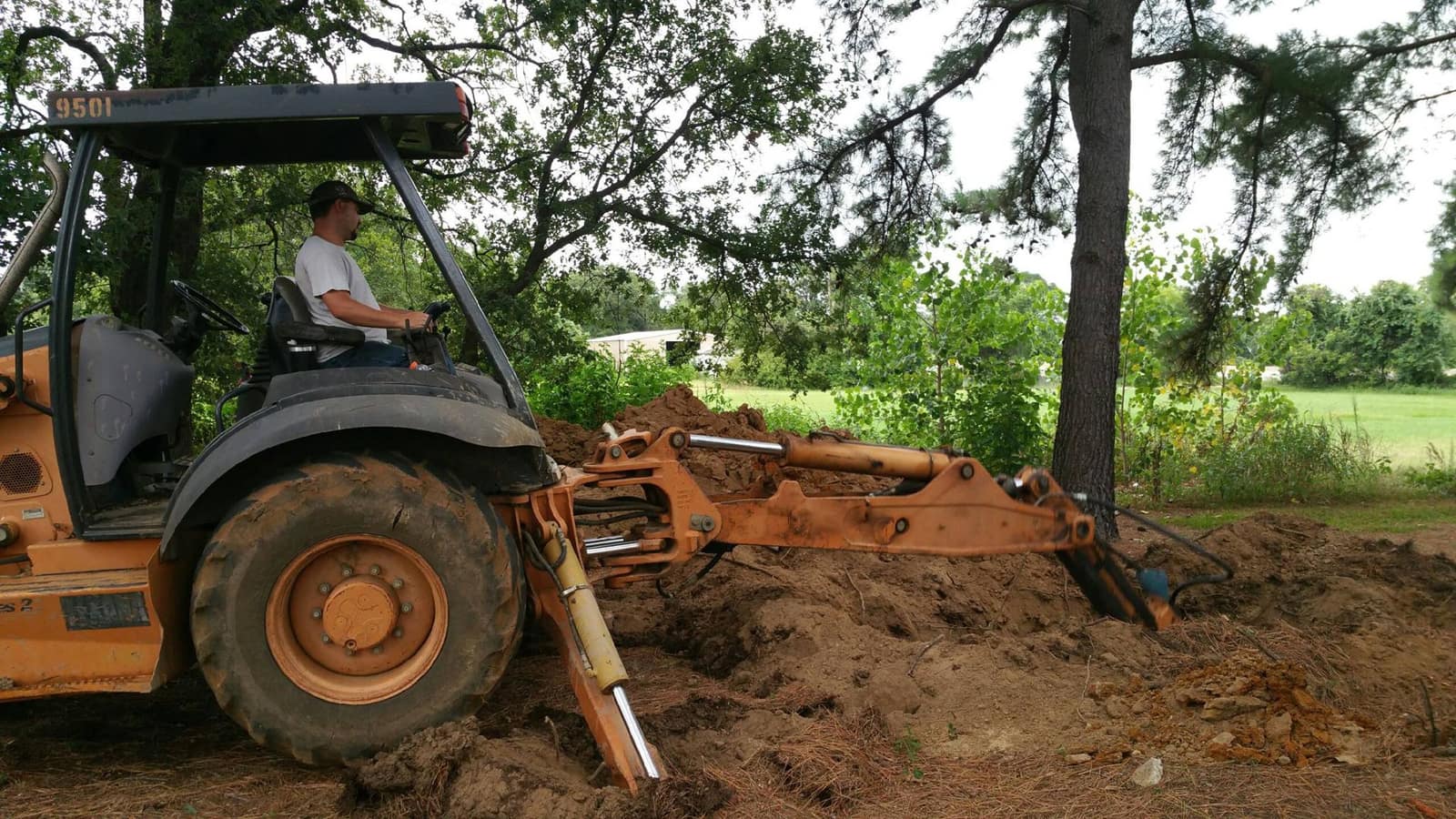 Backhoe digging around a failed drain field for a septic repair in Johnson County, TX