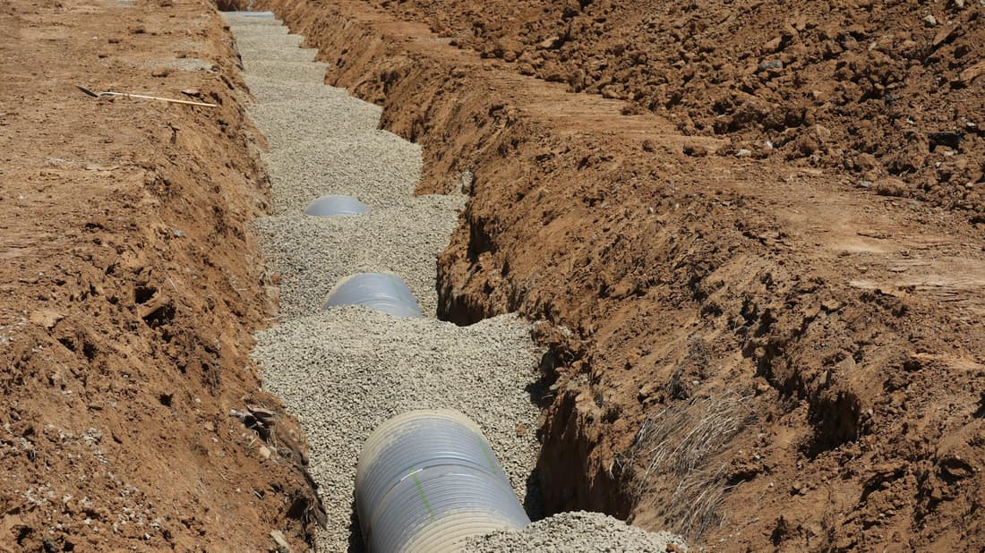Freshly laid septic drain field pipes in a Godley TX trench — what an on-schedule pumping protects