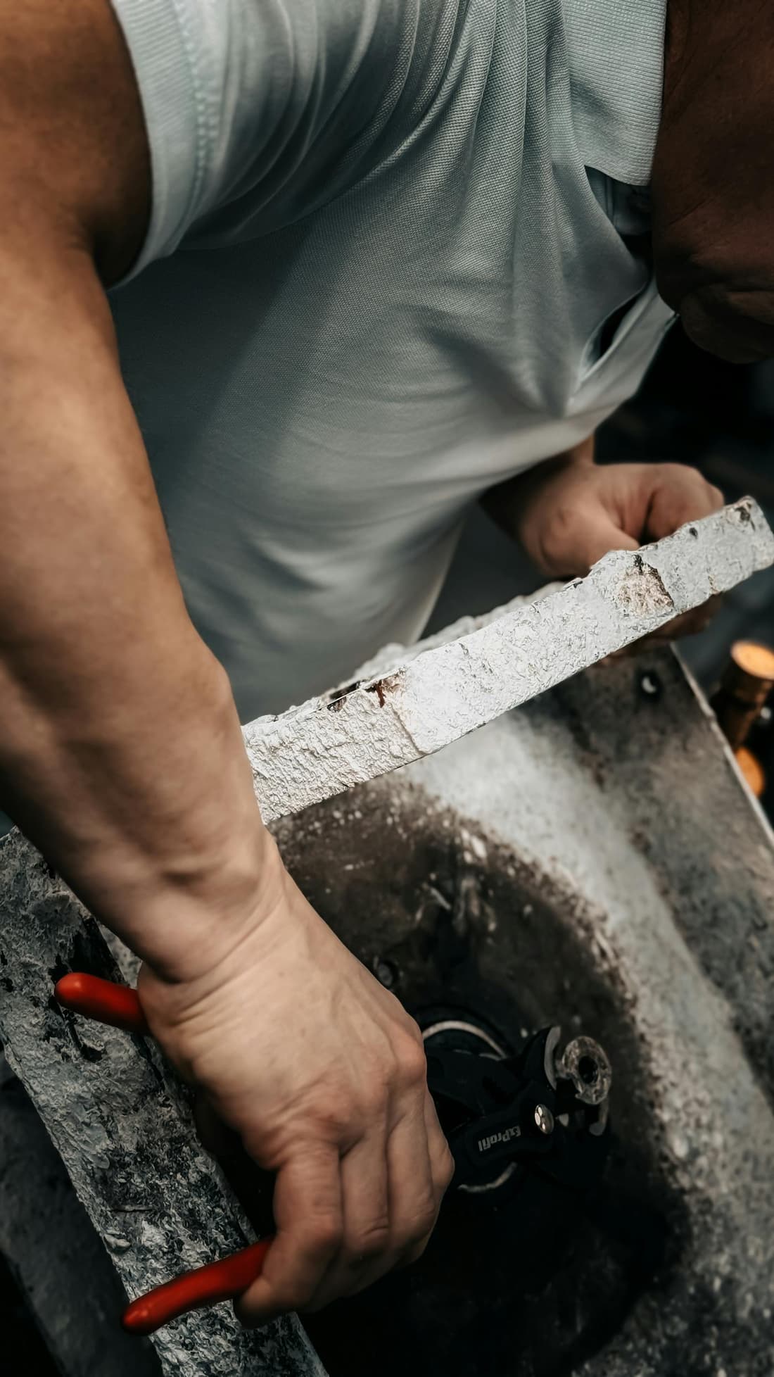 Tradesman hands working a tool over a metal basin — septic repair work in Godley, TX